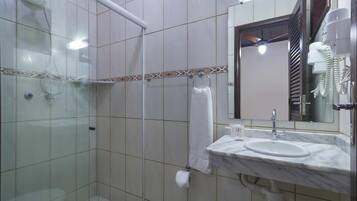 Un baño con cabina de ducha de vidrio, un lavabo con espejo y un perchero para toallas.