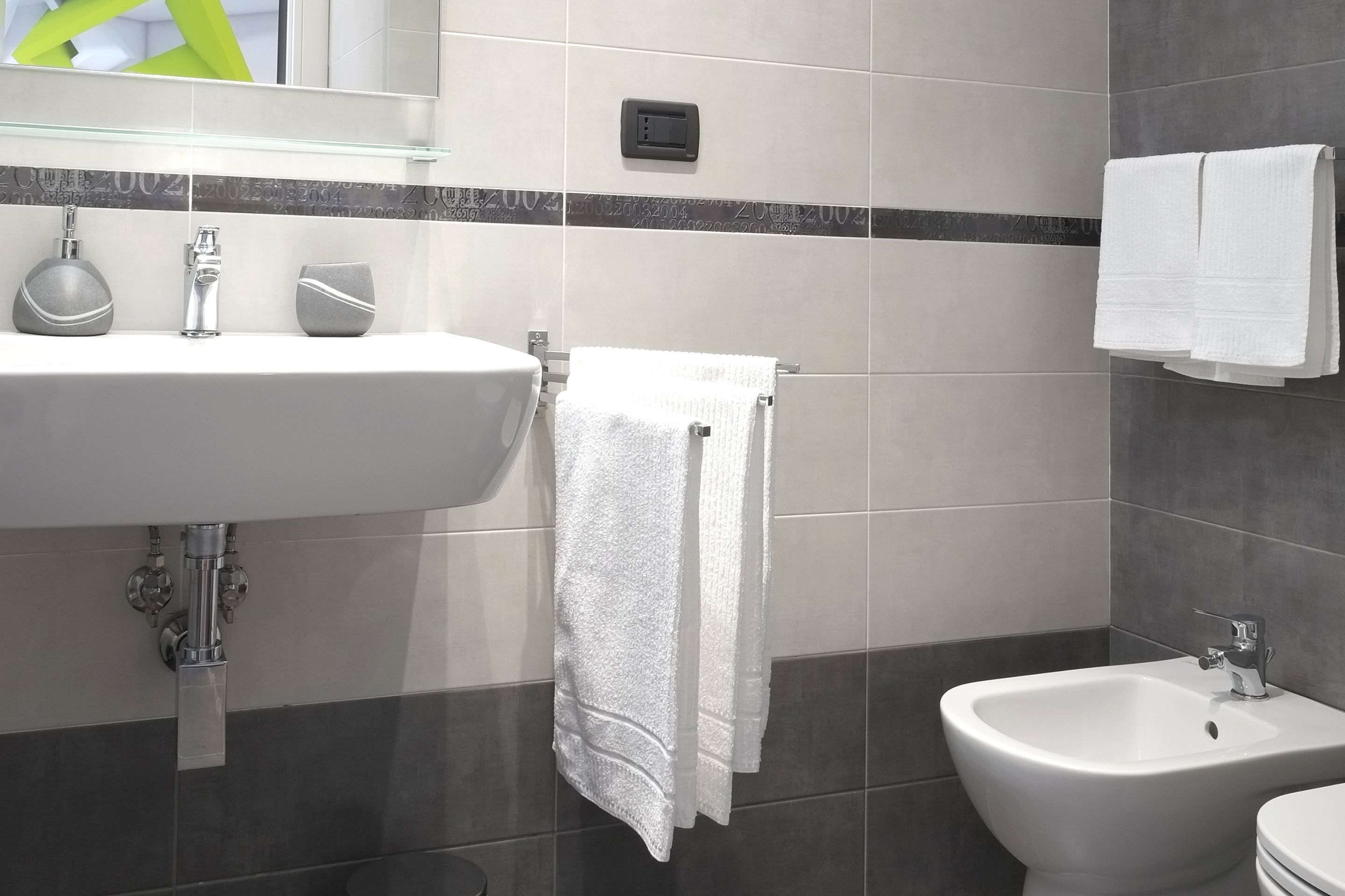 Ein modernes Badezimmer mit einem weißen Waschbecken, einem Bidet und einem Handtuchhalter.