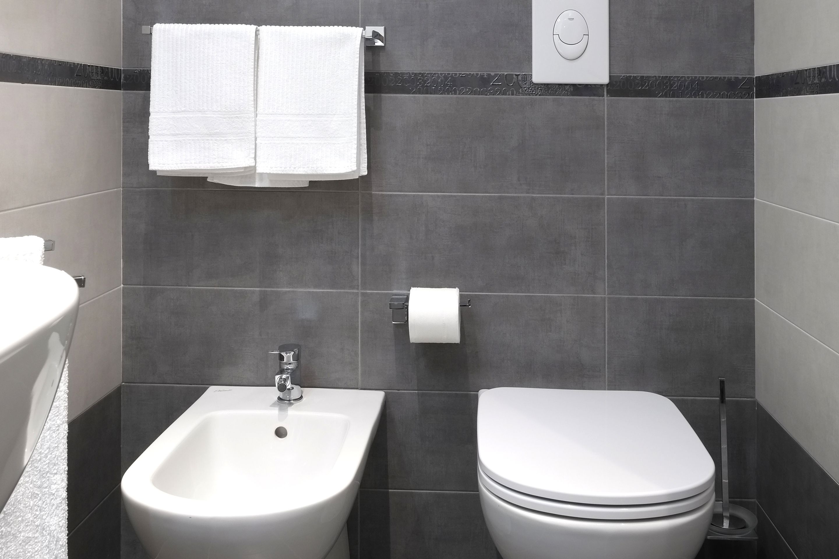 Ein modernes Badezimmer mit integriertem Bidet, Toilette und Handtuchhalter.