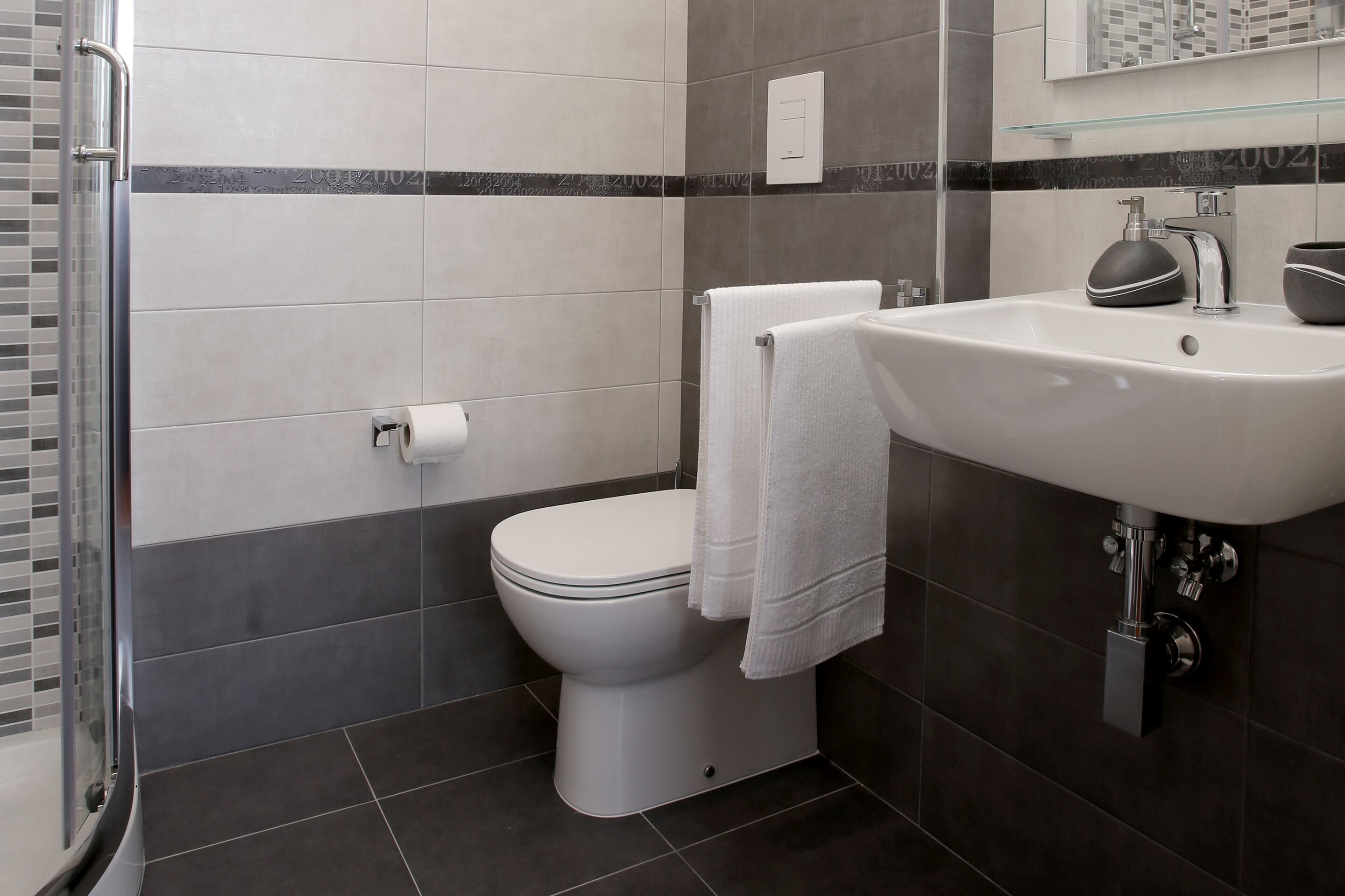 A modern bathroom with a toilet, sink, and glass shower enclosure.