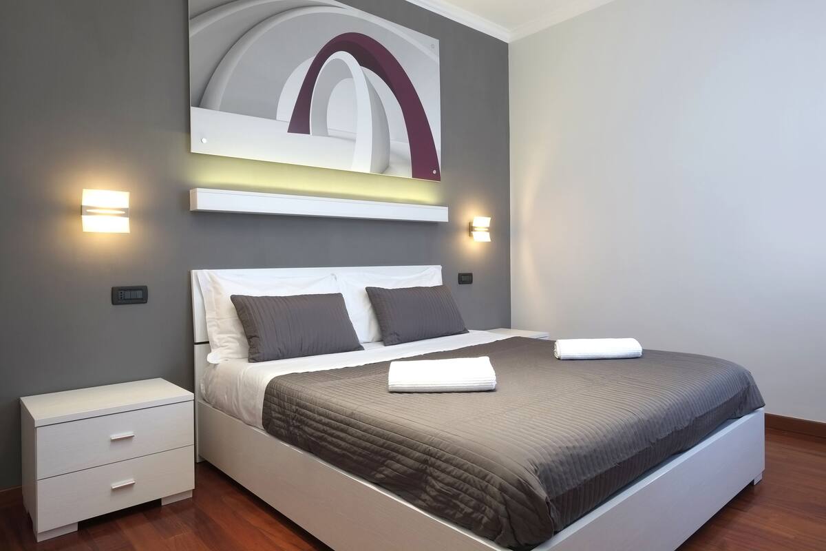 Un dormitorio moderno con una cama grande, mesitas de noche e iluminación empotrada.