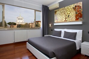 Un dormitorio con una cama grande, una mesita de noche, una ventana con vistas a un edificio y un aire acondicionado de pared.
