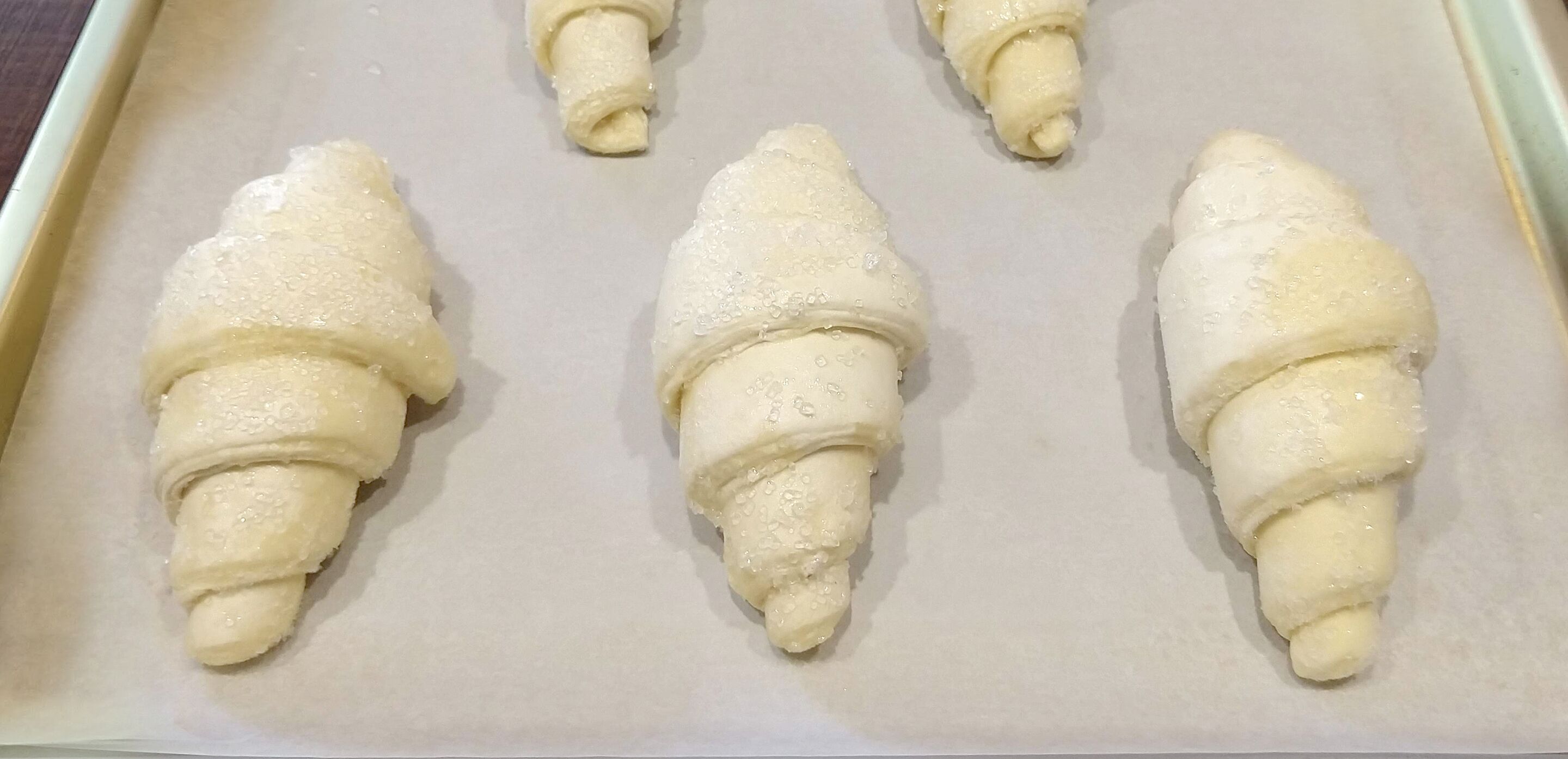 Four croissants on a baking sheet.