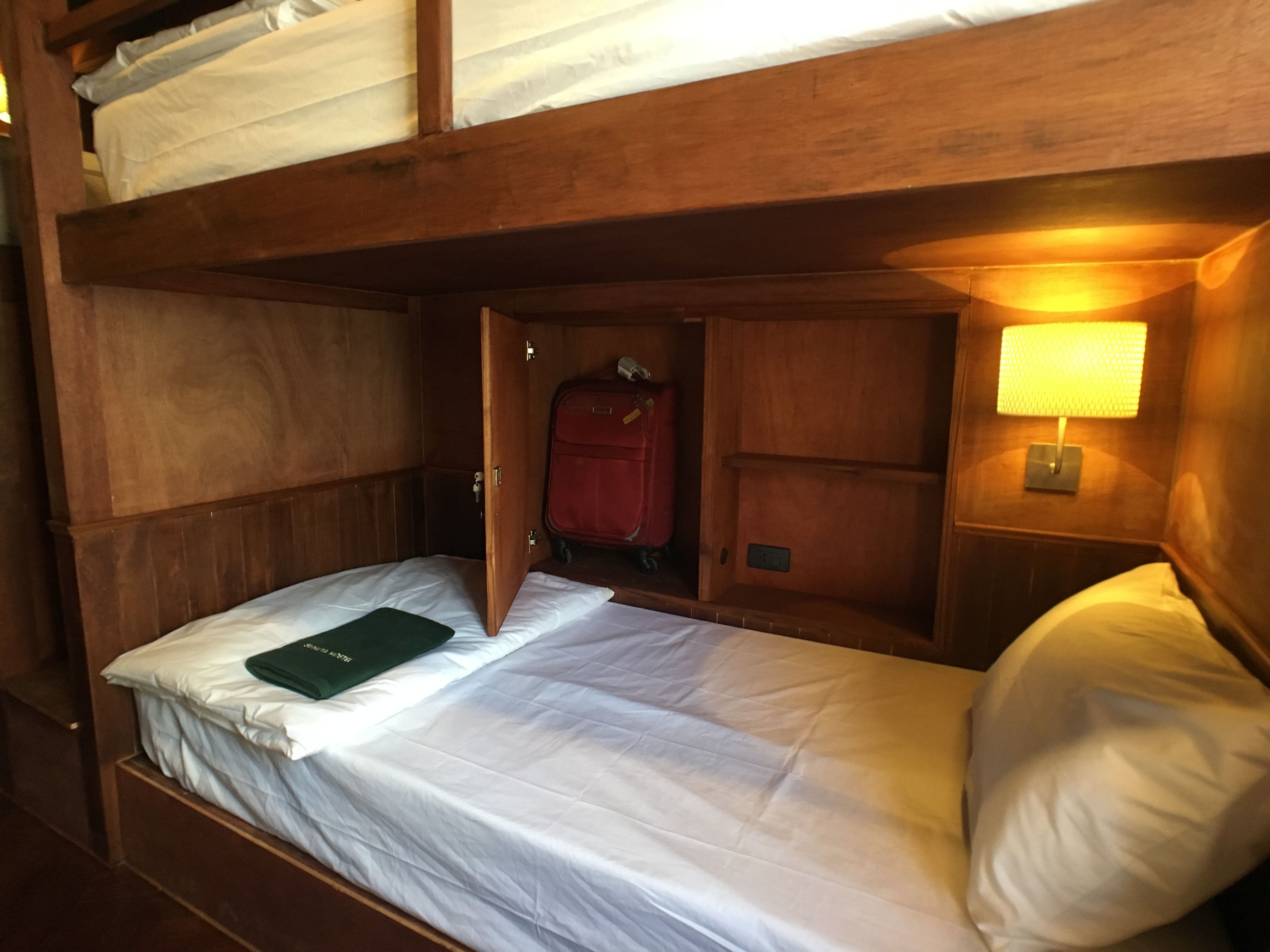 Una cama litera con una maleta y una lámpara en una habitación de estilo rústico.