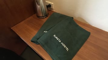 A wooden table with a green towel and a stainless steel kettle.