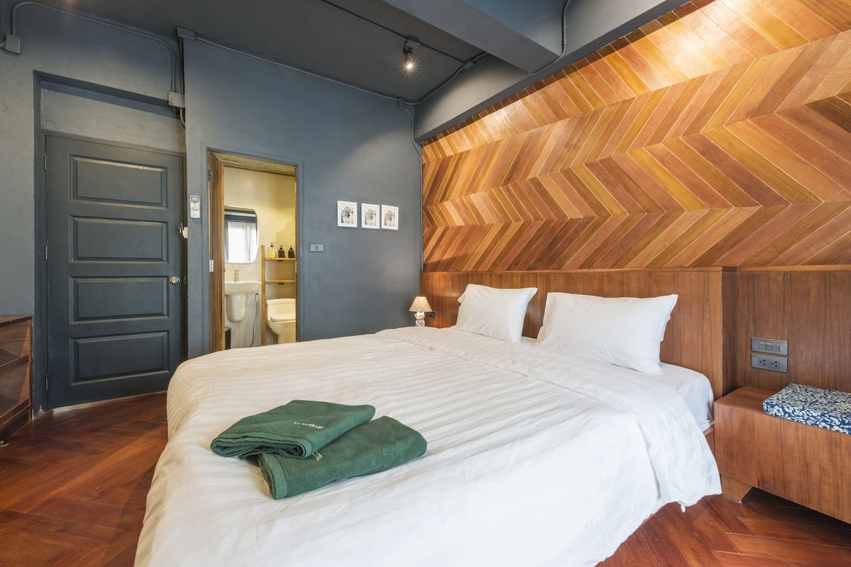 Een hotelkamer met een groot bed, een houten hoofdeinde, een houten vloer en een deur.