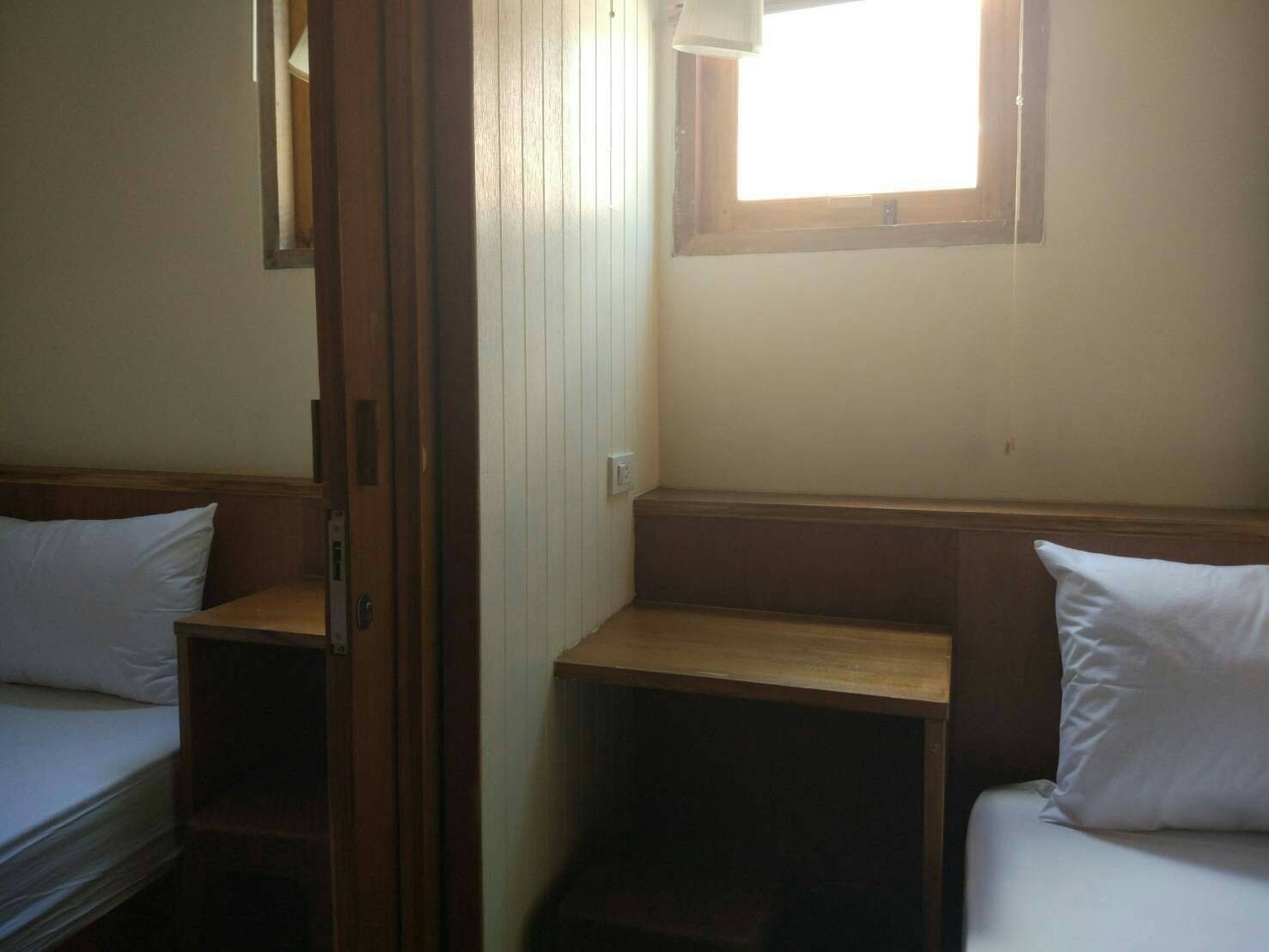 A small, compact room with two beds and a window providing natural light.