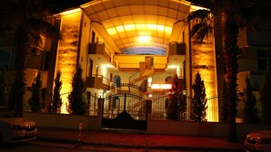 Entrada de hotel con acceso cubierto, camino de entrada portonado y palmeras.
