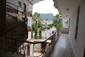 Stunning views of the surrounding landscape unfold from this multi-level space, featuring a central staircase and balcony with a scenic view of palm trees and a distant mountain.