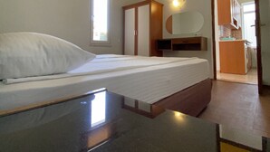 Un dormitorio con cama, armario, espejo y un baño visible a través de una puerta abierta.
