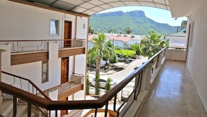 Un balcón con vista a una calle y montañas.