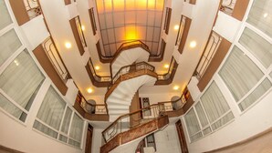 Un atrio de varios niveles con una escalera espiral central, ventanas amplias y un techo alto.