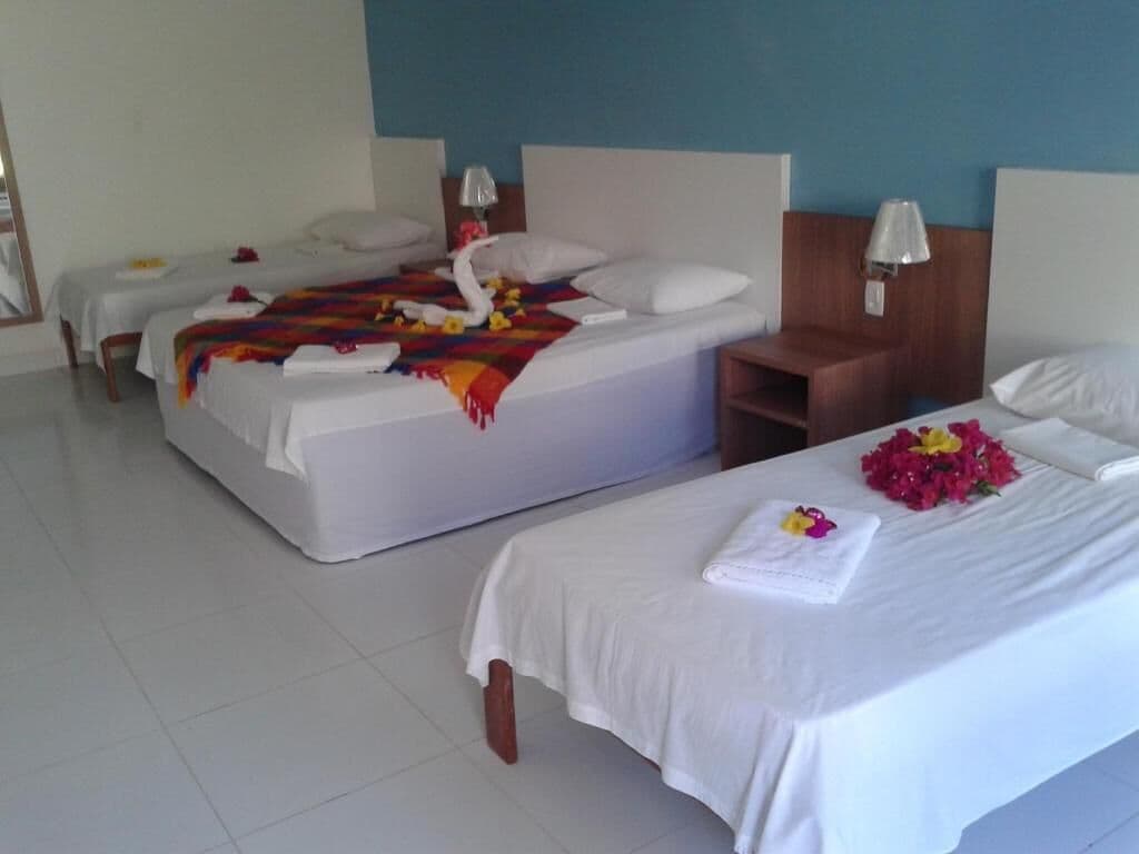 A hotel room with two beds, a wooden nightstand, and a small seating area.