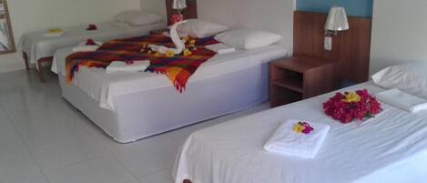 A hotel room with two beds, a wooden nightstand, and a small seating area.