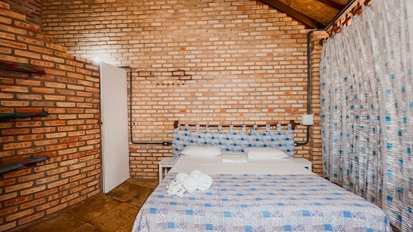 A room with a brick wall, a bed with a quilt, and a curtain. - Ocas do Índio Hotel Spa (Beberibe)
