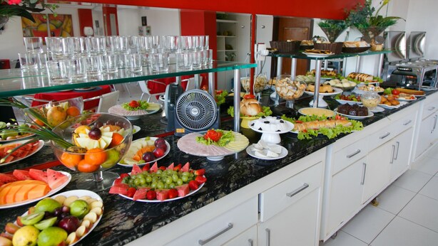 Un buffet proposant une variété de plats et de boissons, notamment des fruits, des salades et des pâtisseries.