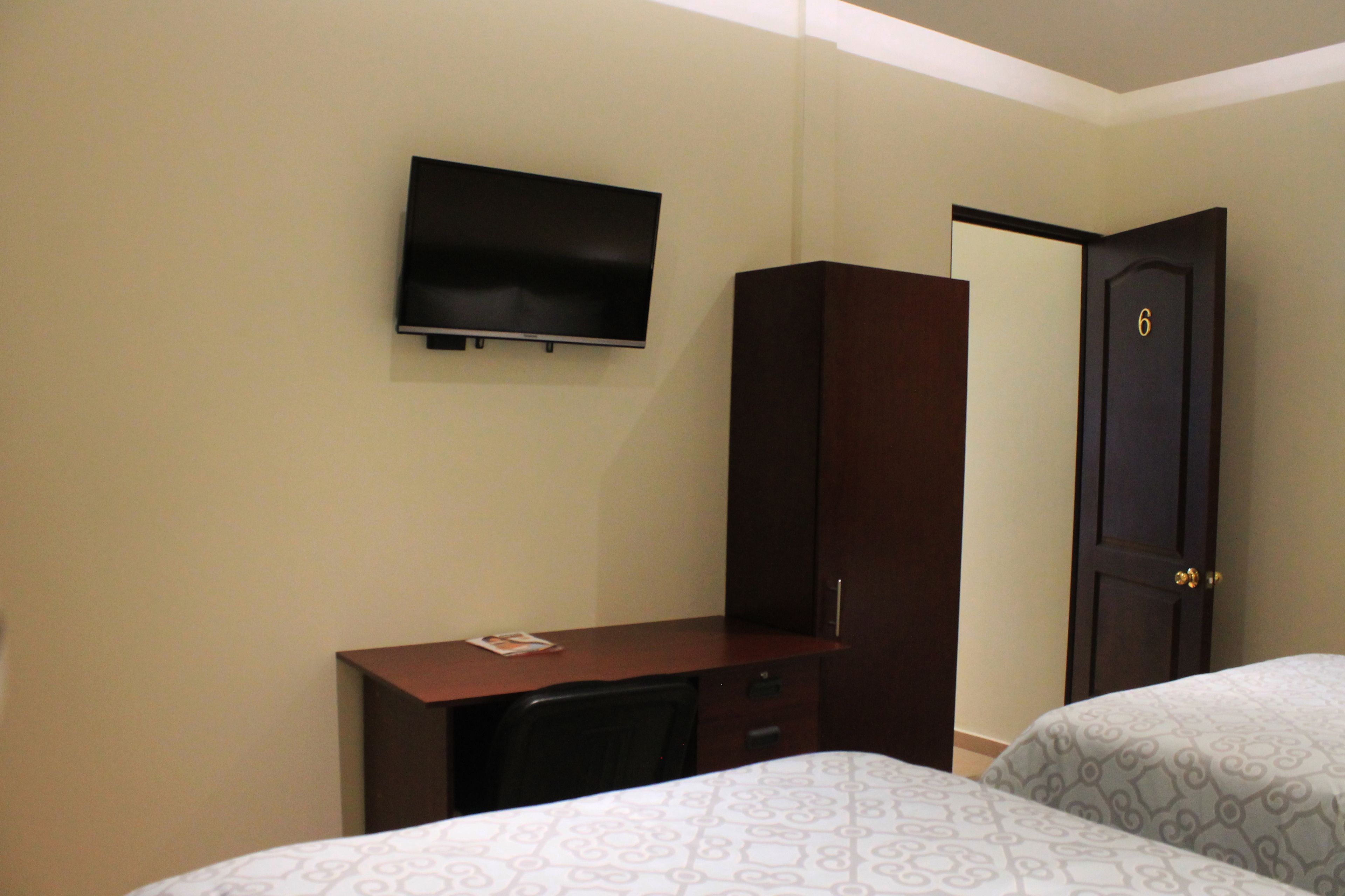 A hotel room with a bed, a desk, a television, and a wardrobe.