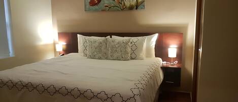 A hotel room with a large bed, two bedside lamps, a floral artwork on the wall, and a nightstand with a phone.