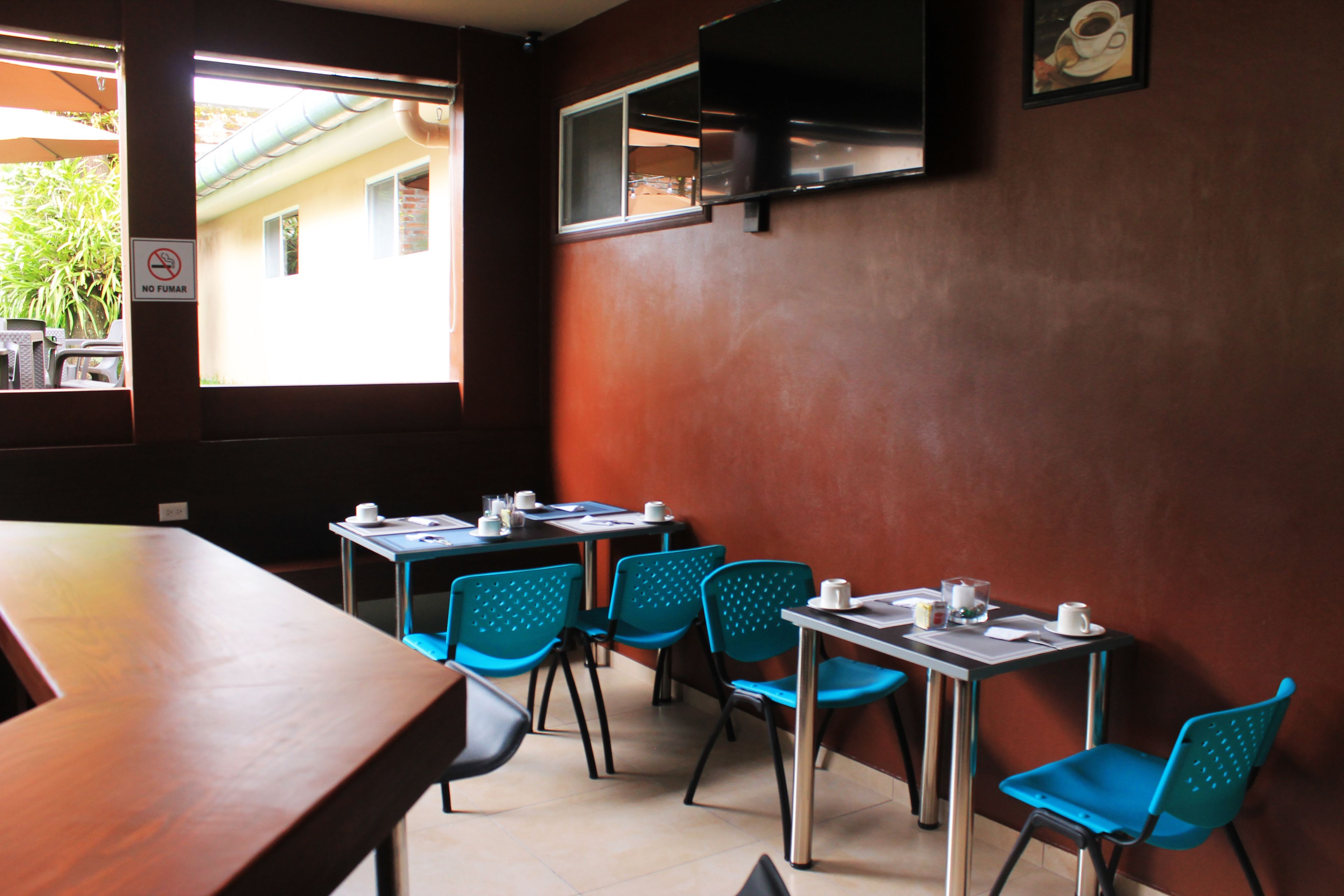 Un espace repas avec des tables et des chaises, une fenêtre donnant sur un paysage agréable et un panneau indiquant qu'il est interdit de fumer.