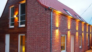 A two-story brick house with a sloped roof, wooden siding, and a covered porch area. - Gite L'archipel (Ellezelles)