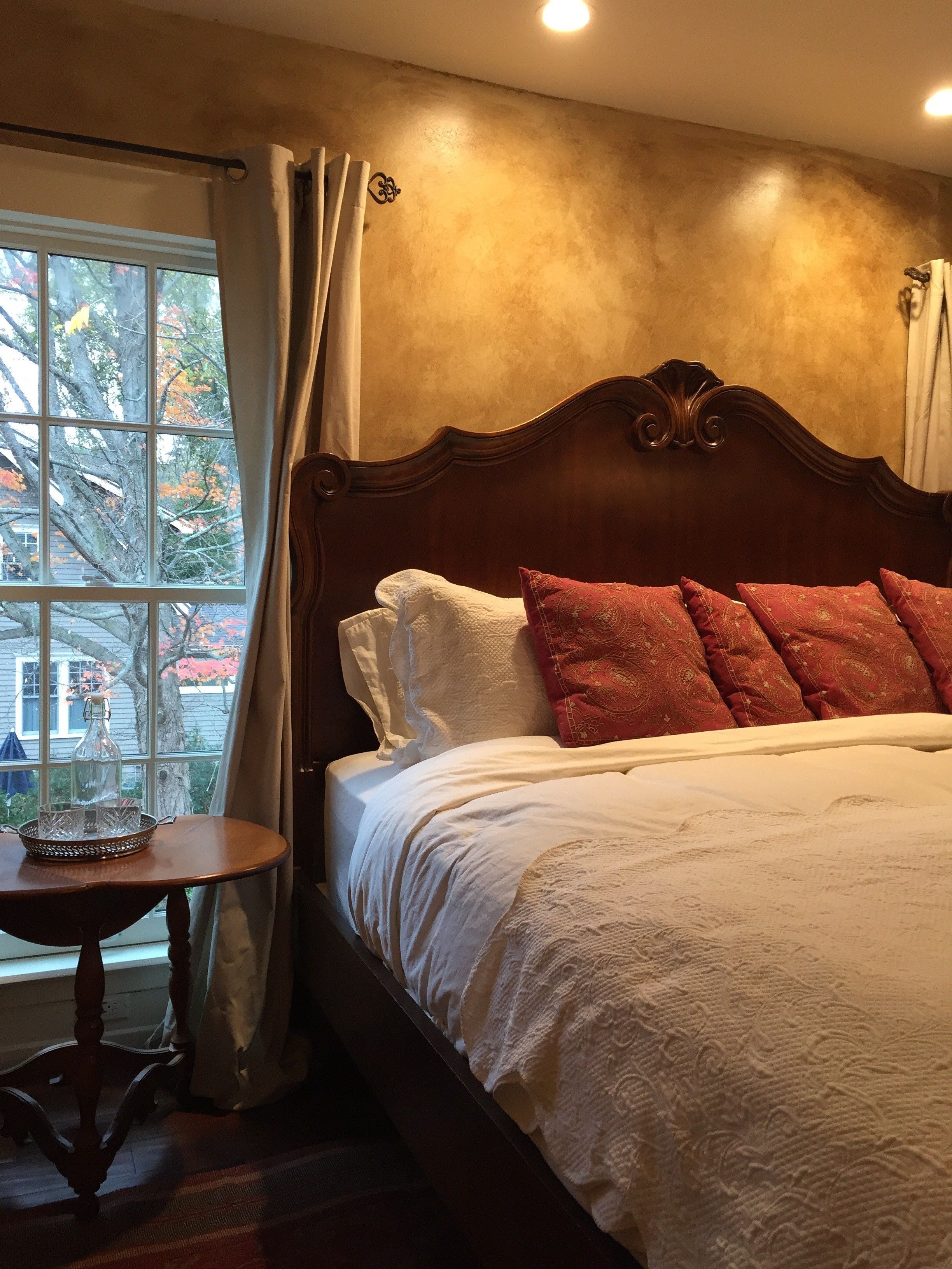 A bedroom with a large bed, a bedside table, and a window with curtains.