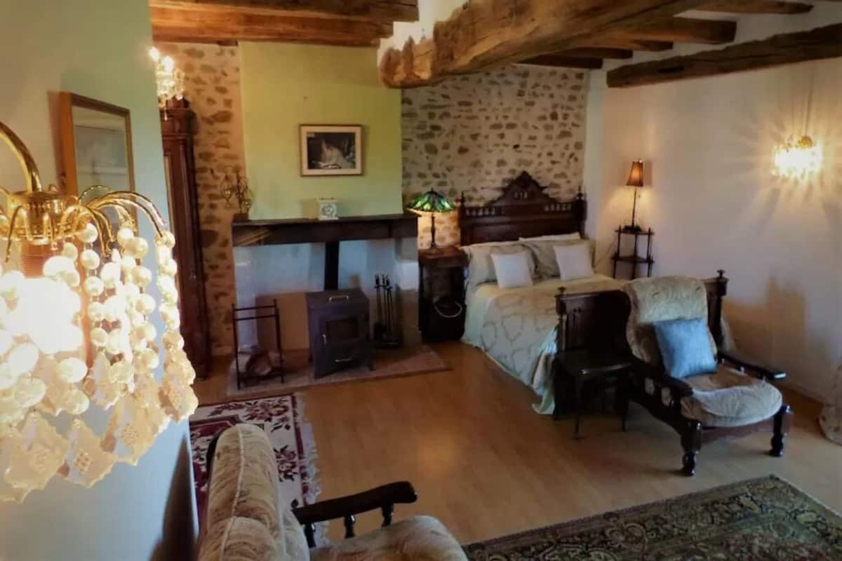 A cozy room with a fireplace, a bed, a chair, and a lamp.