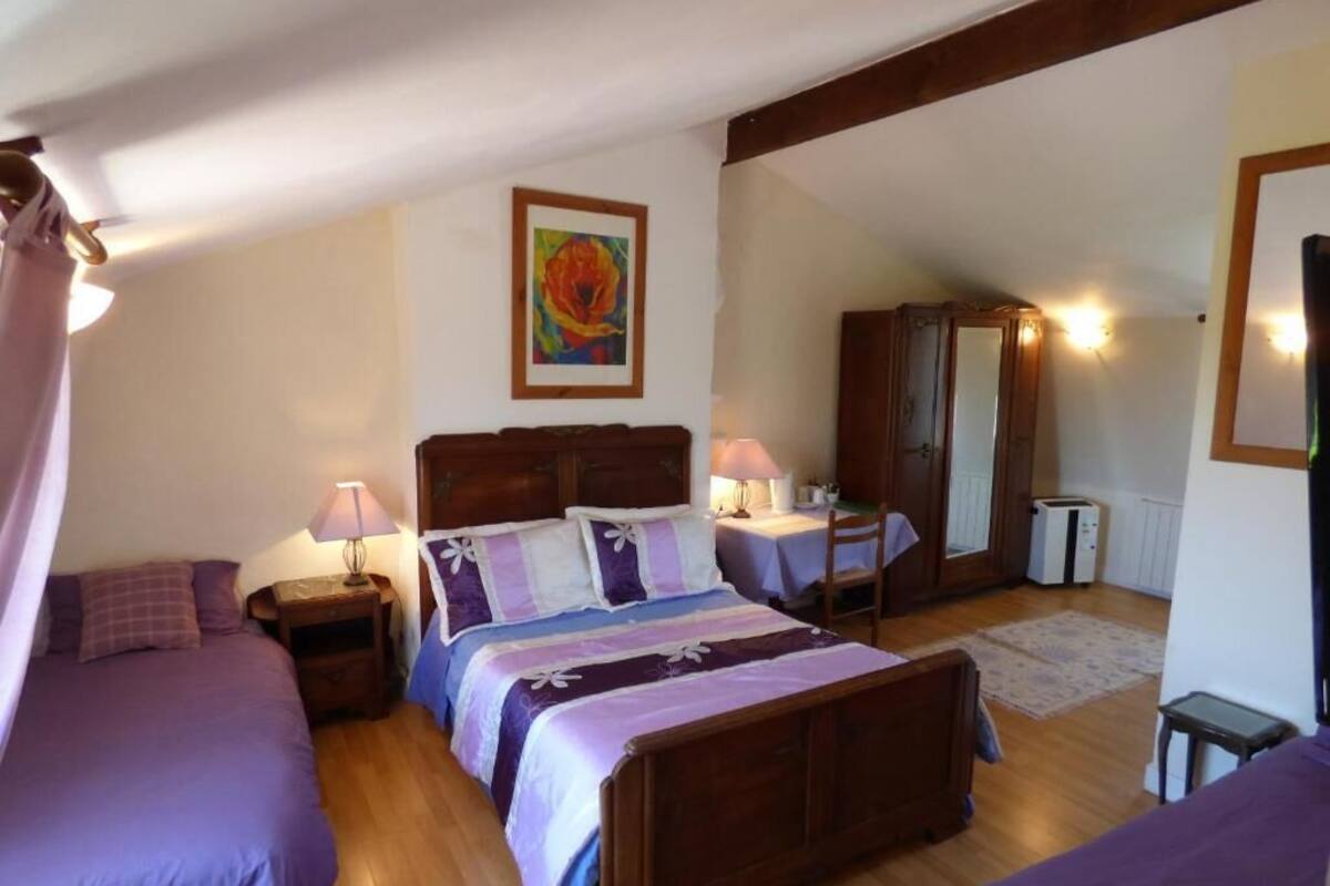 A bedroom with two beds, a wooden headboard, a nightstand, a lamp, a wardrobe, and a mirror.