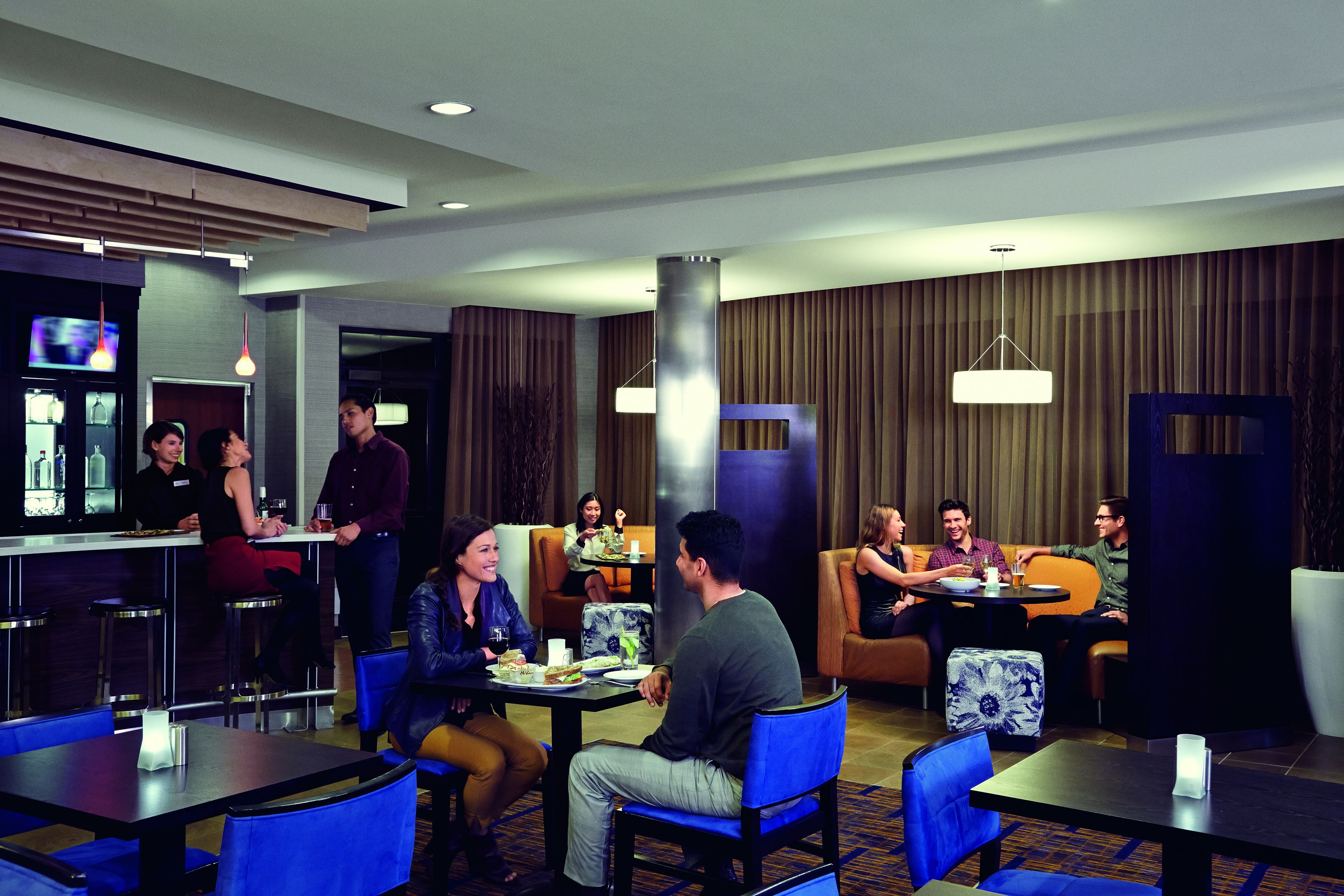 Un vestíbulo de hotel con una zona de bar, espacios para sentarse y un diseño de interiores moderno.