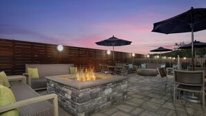 An outdoor patio with stone seating, a fire feature, and umbrellas.