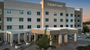 A Courtyard by Marriott hotel with a modern design, featuring a covered entrance and multiple floors.