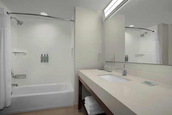 A modern bathroom with a bathtub, a sink, and a large mirror. - Courtyard by Marriott Atlanta Kennesaw (Kennesaw)