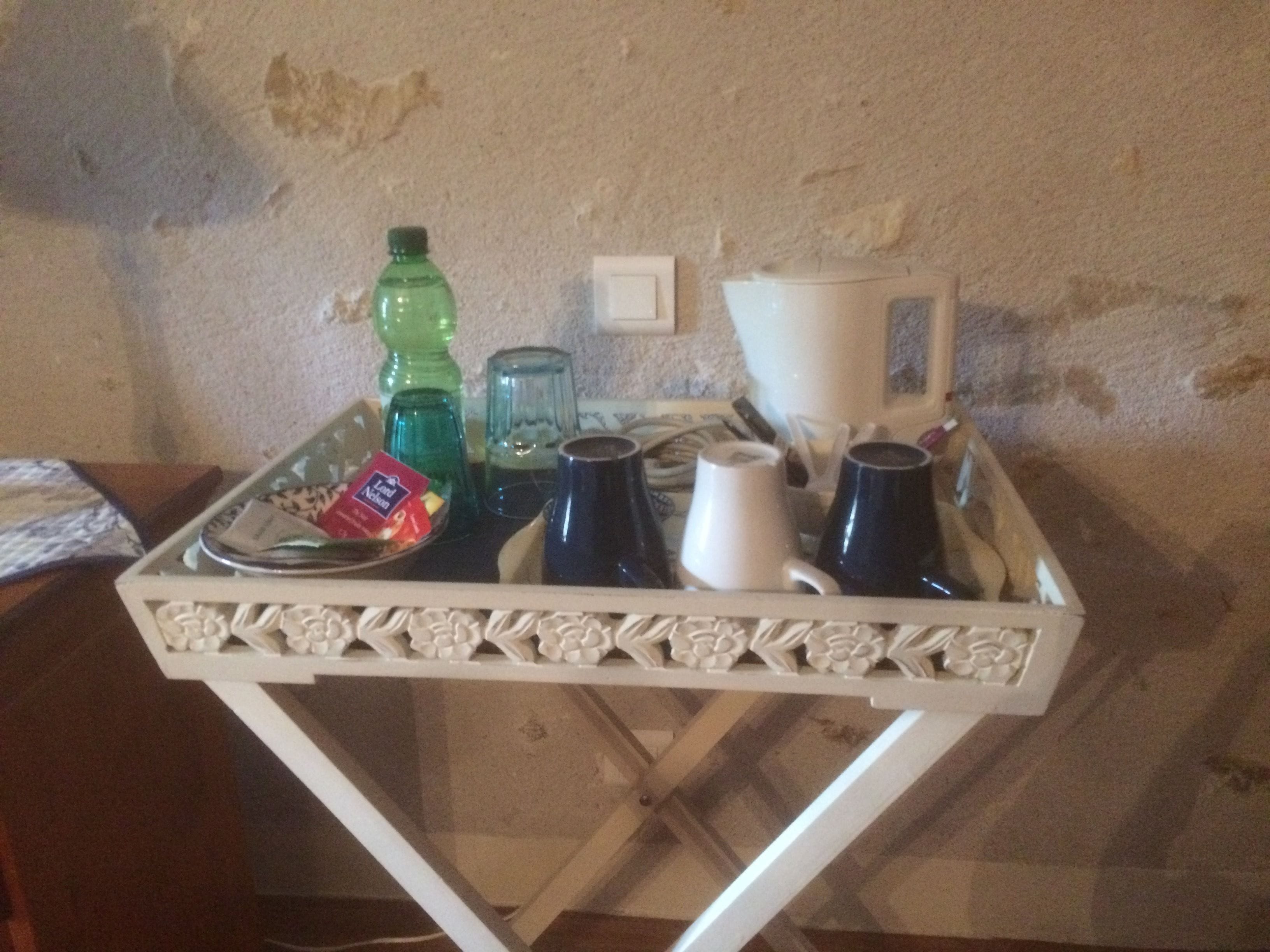 A tray with a bottle, glass, mug, and packet on a table.
