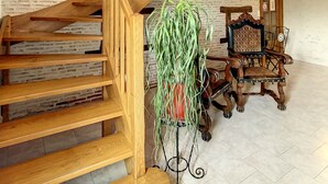 Eine Holztreppe mit einem Verbotsschild, einem gerahmten Bild und einem Stuhl mit einem gemusterten Kissen.