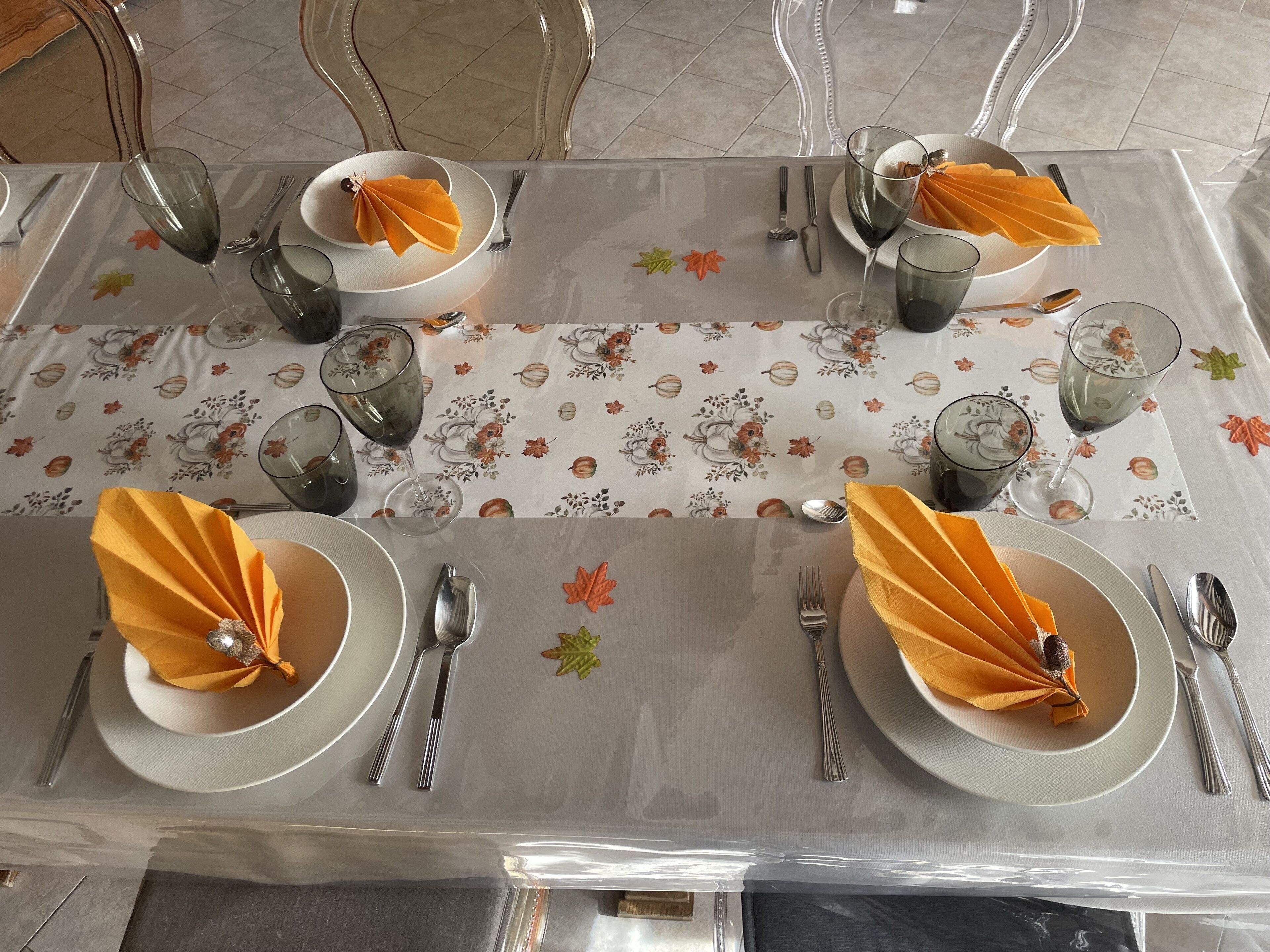 A dining table set with plates, cutlery, and napkins, covered with a floral tablecloth.