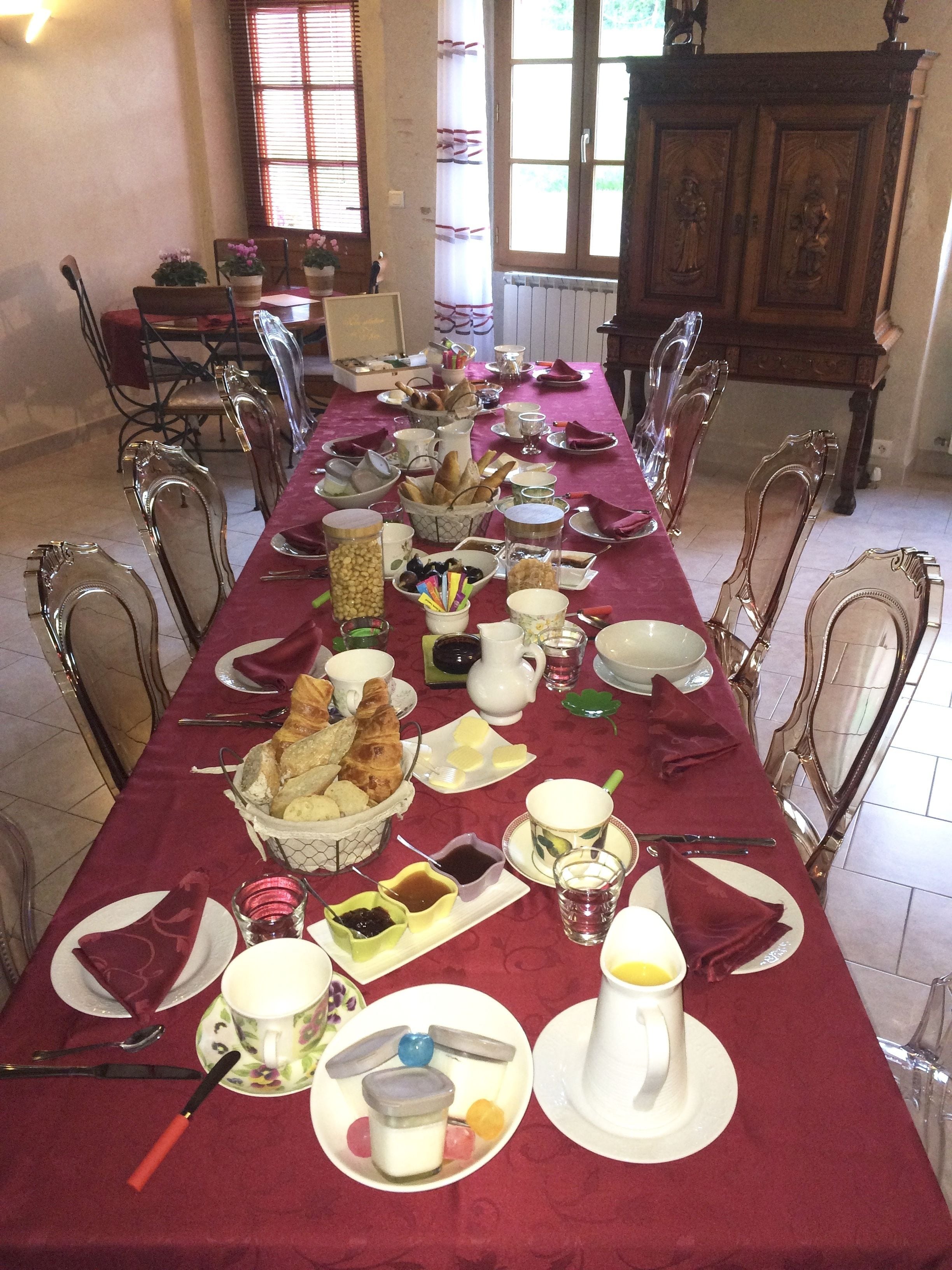 Una larga mesa de comedor dispuesta con varios platos, cubiertos y un mantel rojo.