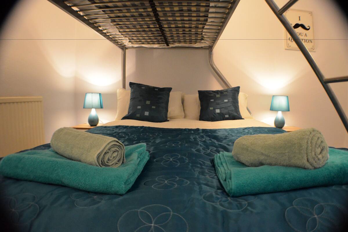 A room with a bunk bed, two bedside lamps, a radiator, and a wall sign.
