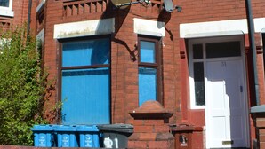 A red brick house with a white door, a satellite dish, and a mailbox. - Birchfields Guest House (Manchester)