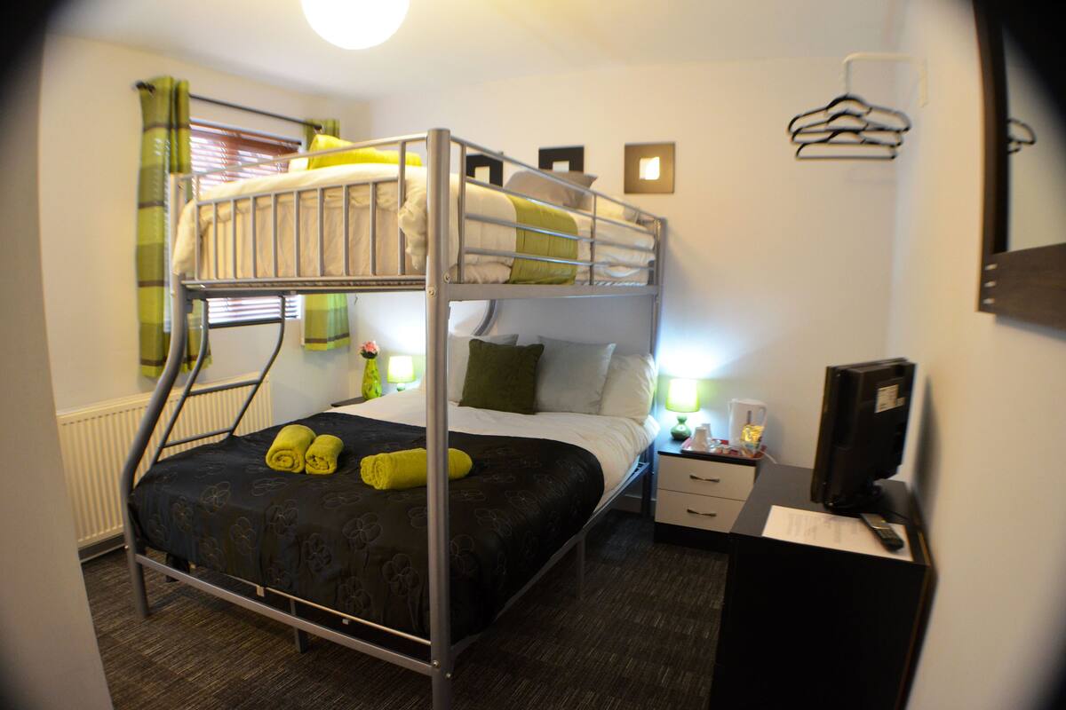 A bunk bed room with a desk, a chair, and a TV.