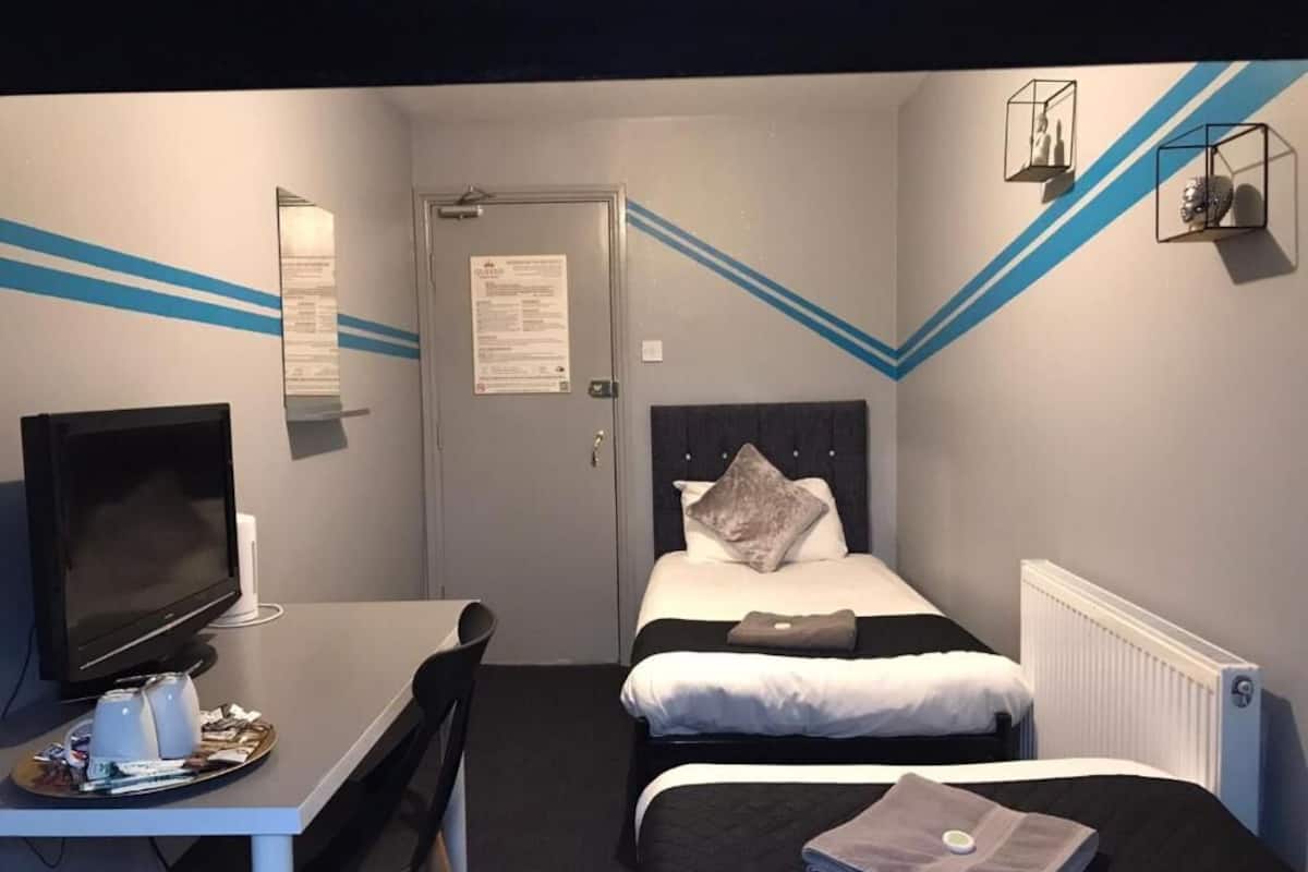 A hotel room with a bed, a desk with a computer, and a television.
