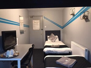 A hotel room with a bed, a desk with a computer, and a television. - Queens Guesthouse Manchester (Manchester)