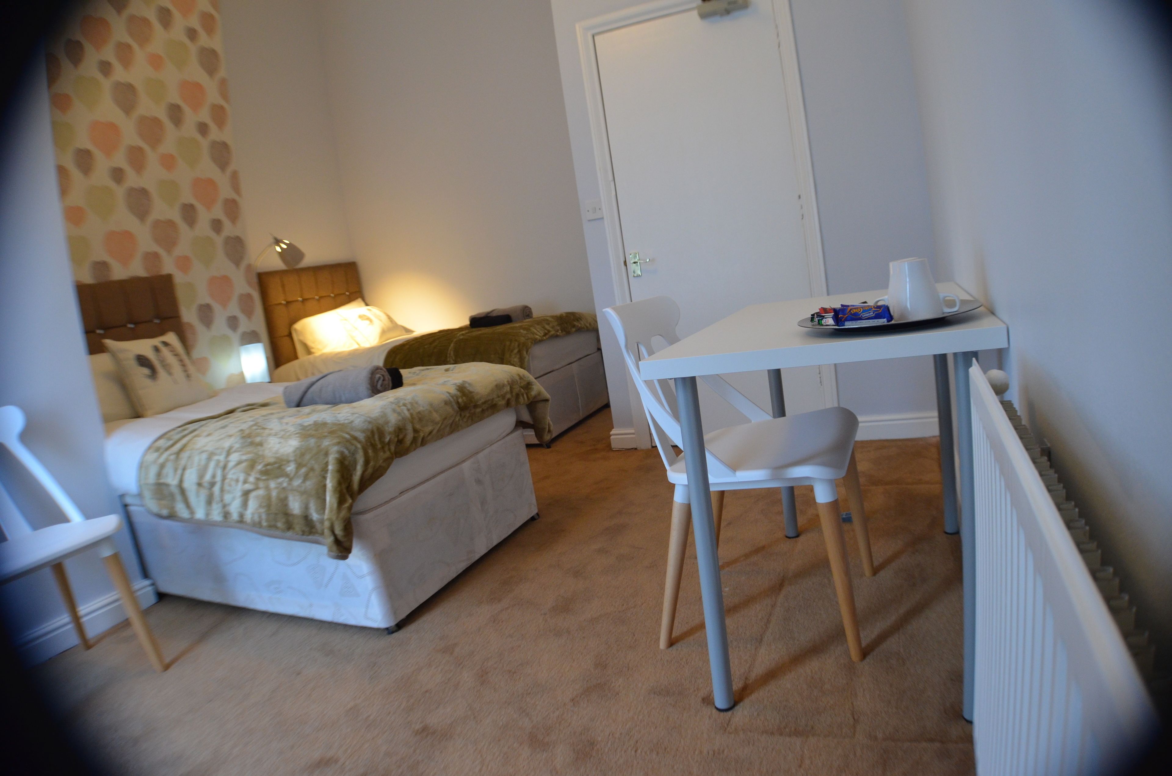 A small, neatly arranged bedroom with a bed, bedside table, and a chair.