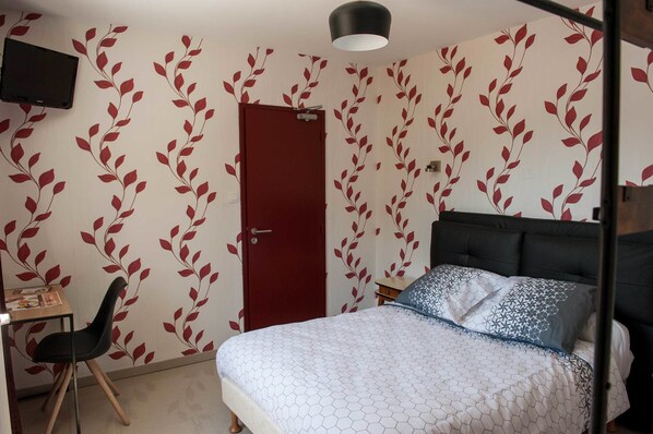 Un dormitorio con cama, escritorio, silla y puerta.