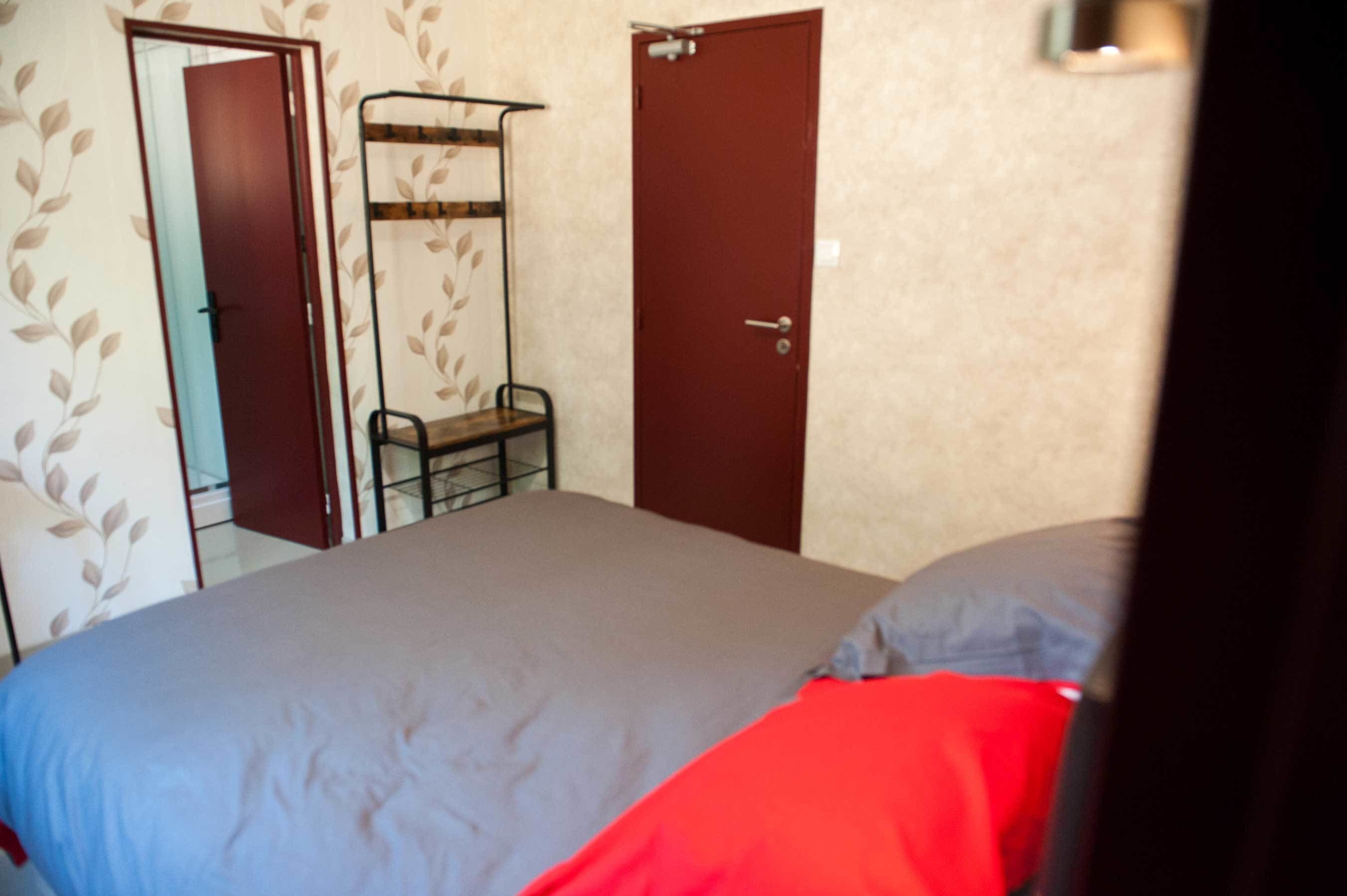 A bedroom with a bed, a wardrobe, and a door.