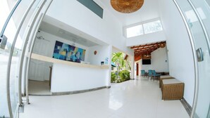 A spacious hotel lobby with a reception desk, a dining area with chairs and tables, and a ceiling fan. - Hotel Isla Bonita (San Andrés)