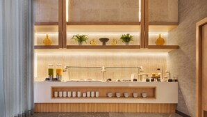 A modern reception area with a wooden counter, shelves with decorative items, and a glass partition. - Hilton Garden Inn Chihuahua (Chihuahua)