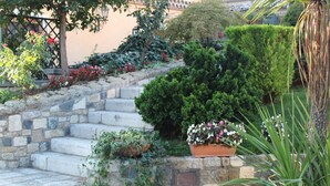 Una escalera de piedra que conduce a un edificio, rodeada de abundante vegetación y plantas con flores.