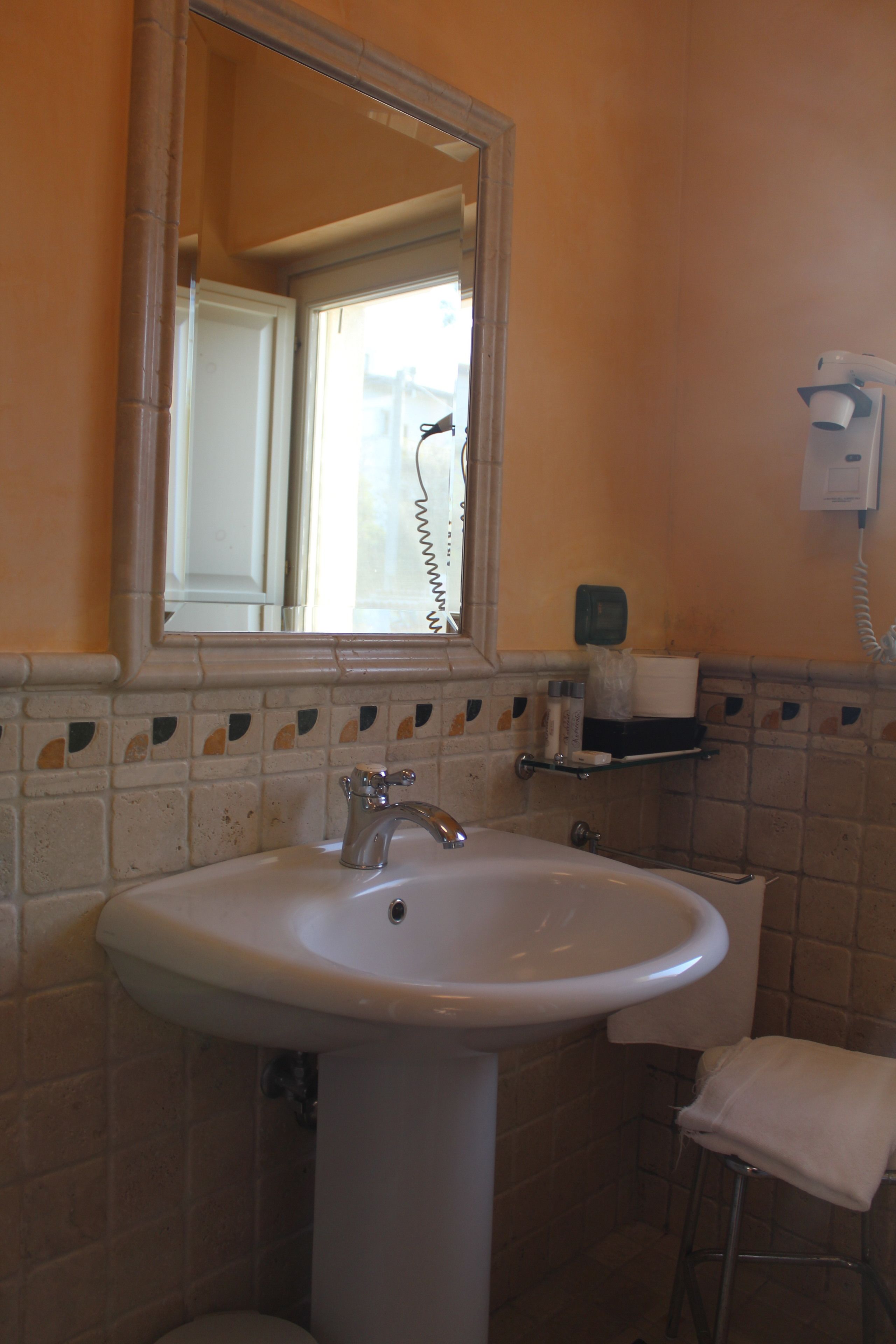 Casa de banho com lavatório branco, espelho e porta-toalhas.