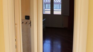 Un pasillo con suelo de madera, pared de azulejos y una puerta que da a otra habitación.