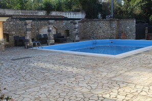 Una piscina con muros y patio de piedra.