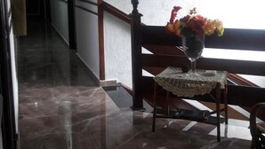 A hallway with a marble floor, a wooden railing, and a table with a vase of flowers. - Hotel Flor da Vila Mariana (São Paulo)